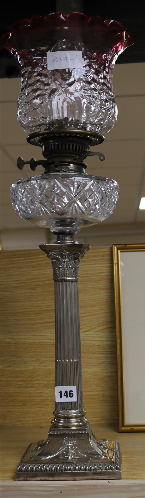 A silver plated oil lamp with cranberry shade